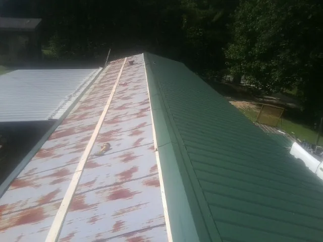 Old rusted panels beside newly installed green metal roofing — Wind Damage Roof Repair by Roofing Brothers in Waterloo