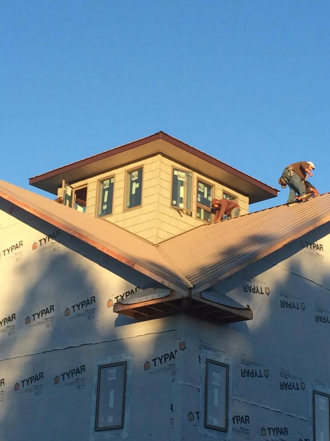 Roofers working around a rooftop cupola on a new metal roof at sunset — Roof Waterproofing in Waterloo by Roofing Brothers